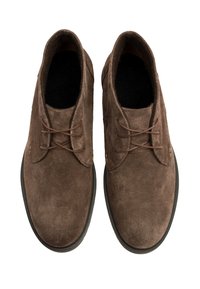 Brązowe zamszowe buty o gładkiej fakturze, zaokrąglonym nosie i dwóch parach dziurek na sznurowadła. Szczegółowe przeszycia wokół krawędzi.