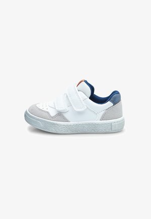 White sneaker with velcro straps and grey suede accents. Rounded toe, textured rubber sole, and blue textile lining. Compact design.