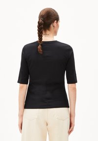 Schwarzes, eng anliegendes Shirt mit kurzen Ärmeln, aus glattem Stoff gefertigt, mit Rundhalsausschnitt und dezenten Nähten auf der Rückseite.