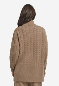 Brauner Kabelstrickpullover mit hohem Kragen, mit geripptem Saum und Schulterdetails, aus strukturiertem Strickstoff gefertigt.