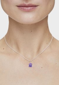 Collar de cadena de plata con un colgante púrpura en forma de oso, con una textura suave y un detalle intrincado en la superficie.