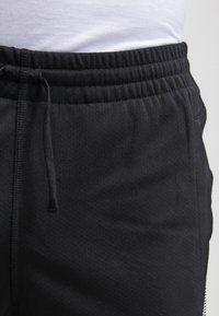 Černé sportovní šortky s texturovanou tkaninou, elastickým pasem se šňůrkou a bočními kapsami. Jednoduchý design bez viditelných vzorů.