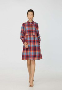 Robe à carreaux rouge et bleu avec des manches longues, devant à boutons, col et jupe évasée, fabriquée à partir d'un tissu doux.