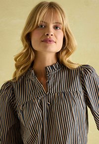Striped blouse featuring vertical navy and beige stripes, button closure, and gathered detail at the bust. Lightweight fabric with a soft texture.