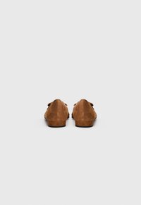 Pair of brown suede flat shoes with low heels shown from the back on a plain white background.