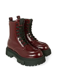 Błyszczące bordowe buty wojskowe zapinane na sznurówki z grubą czarną podeszwą z rowkami i pętlami z tyłu, pokazane obok siebie na białym tle.