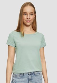 T-shirt en coton vert menthe avec des manches courtes retroussées et un col rond classique, présenté sur un fond neutre.