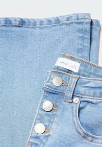 Jean en denim bleu clair, avec une taille haute, des boutons en métal argenté, une poche avant standard et des détails de coutures visibles.