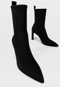 Bottines noires en tissu lisse, dotées d'un bout pointu, d'un talon stiletto haut et d'un design élégant et ajusté.