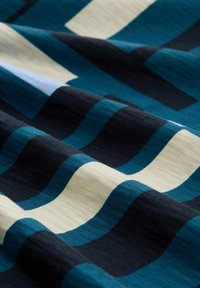 Close-up van een stof met blauwe, zwarte en crèmekleurige horizontale strepen, die textuur en zachte plooien toont.