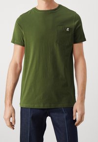 Camiseta de algodón verde oliva con mangas cortas y un bolsillo delantero, con una pequeña etiqueta de logo. Textura suave y diseño clásico de cuello redondo.