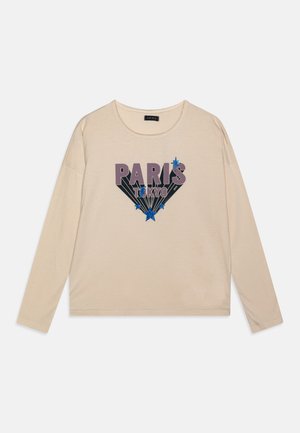 Beige long-sleeve t-shirt made from soft fabric featuring "PARIS" and "TOKYO" graphics in purple and blue with star accents.