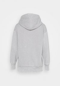 Šedá mikina s kapucí, která má mírně texturovaný povrch, spadlé ramena a žebrované manžety. Jednoduchý, minimalistický design bez zdobení.