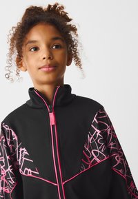 Black zip-up jacket with pink graphic accents and stitching. Features a high collar and textured design on sleeves. Suitable for active wear.