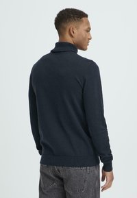 Navy blue turtleneck sweater with long sleeves, ribbed cuffs, and hem. Soft texture, form-fitting design, viewed from the back.