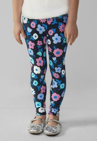 Damskie legginsy w kwiatowy wzór w kolorze granatowym z kolorowymi kwiatami w odcieniach różu, niebieskiego i białego; połączone z srebrnymi balerinami.