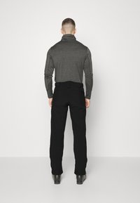 Black trousers with a tailored fit, paired with a dark gray long-sleeve top featuring a high collar. Smooth texture, minimal detailing.