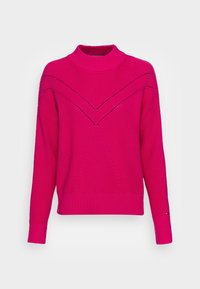 Pull en tricot rose à col montant, avec un motif texturé et des découpes diagonales sur la poitrine et les épaules.