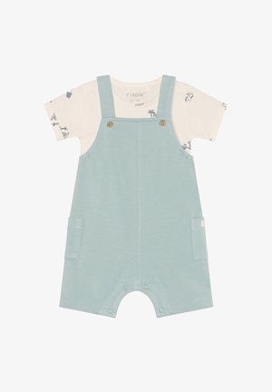 Lyseblåt bomuldsoverall med justerbare stropper, træknapper og sidelommer, lagdelt over en hvid kortærmet skjorte med blå tryk.