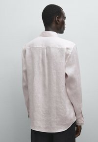 Light pink, long-sleeve shirt in linen fabric features a classic collar and buttoned cuffs, with a relaxed fit and subtle texture.