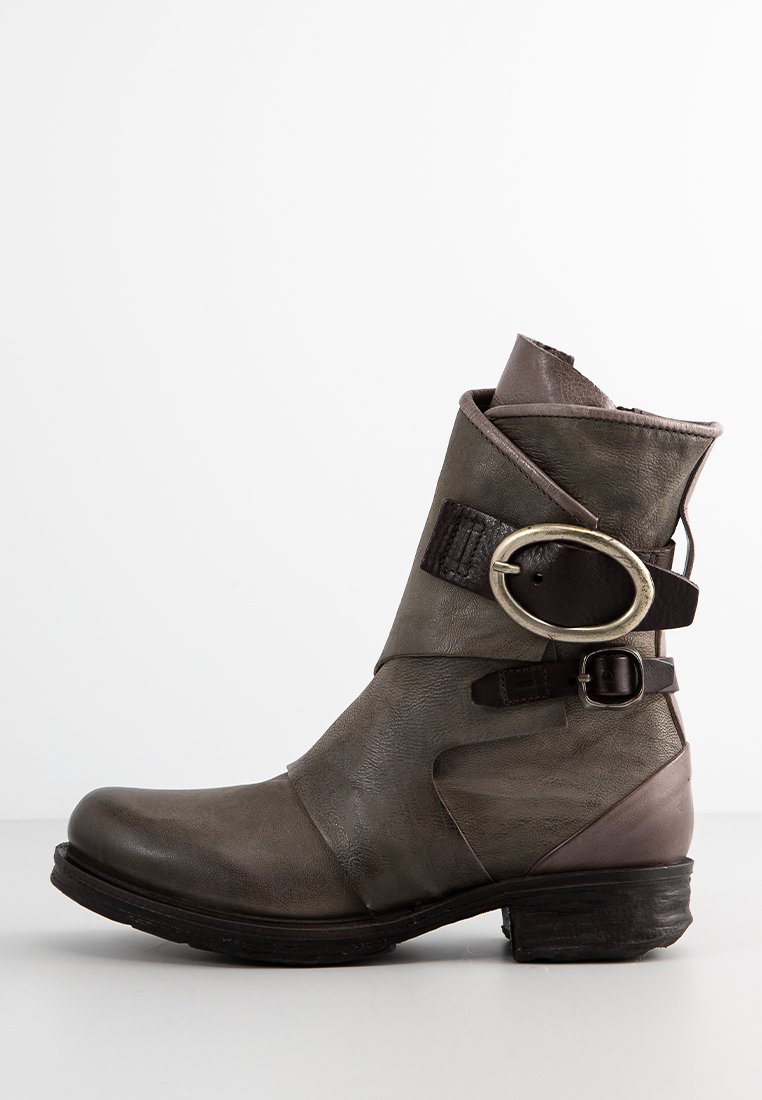 Bottine en cuir vert olive avec un accent marron, présentant une large sangle et une boucle en métal décorative sur le côté. Semelle en caoutchouc plate.