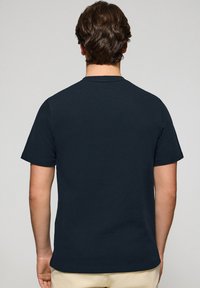 Mörk marinblå t-shirt med kort ärm, klassisk crew neck, enkel design och ett slätt, texturerat tyg. Inga synliga grafiska element eller detaljer.