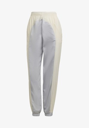 Pantaloni de trening gri deschis și crem, cu talie elastică, glezne strâmte și panouri laterale decorative, având un logo adidas pe soldul stâng.