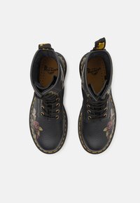Botine negre din piele pentru gleznă, cu broderie florală, boturi rotunde, modele de trandafiri verzi și roz, cusături galbene și sistem de șireturi.