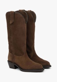 Hnědé semišové kovbojské boty s vysokým svrškem, zakřiveným vrškem a jemným třásňovým detailem, s blokovým podpatkem a černým lemem.