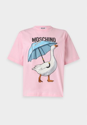 Kobieta nosząca różowy t-shirt Moschino z nadrukiem gęsi i parasola, czarną spódnicę z różowym futrzanym wykończeniem oraz czarne szpilki na pasku wokół kostki.
