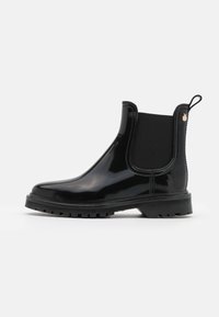 Botas Chelsea de goma negra con paneles laterales elásticos, punta redondeada, suela texturizada y una lengüeta en la parte posterior para facilitar su uso.