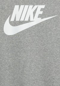Grijze katoenen sweatshirt met een groot wit Nike-logo. De textuur is zacht en glad, met een klassieke ronde halslijn en korte mouwen.