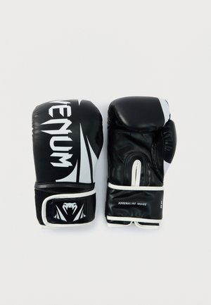 Paire de gants de boxe Venum noirs et blancs, l'un montrant le devant avec le logo, l'autre montrant la paume avec le texte "Adrenaline Inside".
