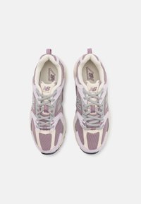 Paire de chaussures de course New Balance violettes et beiges avec des lacets gris vue de dessus sur fond blanc.