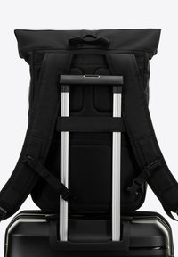 Mochila negra con correas ajustables y cierre enrollable, que cuenta con un panel trasero texturizado y un asa de trolley integrada.