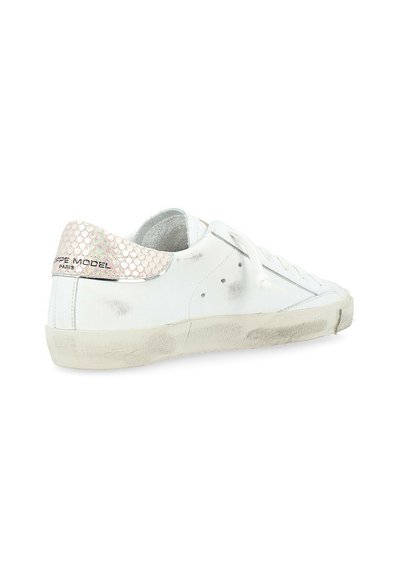 Sneaker in pelle bianca con un accento pastello rosa testurizzato sul tallone, lacci piatti e sottili segni di usura all'esterno e sulla suola.