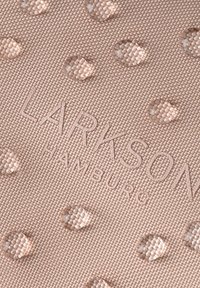 Tessuto strutturato in rosa tenue con punti in rilievo; presenta un testo stampato in rilievo "LARKSON HAMBURG" in un design sottile per il branding.