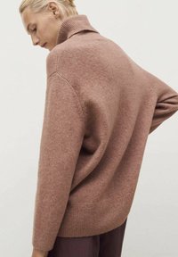Beige rolák ze měkké pleteniny, který má volný střih, žebrovaný lem a design s kleslými rameny.