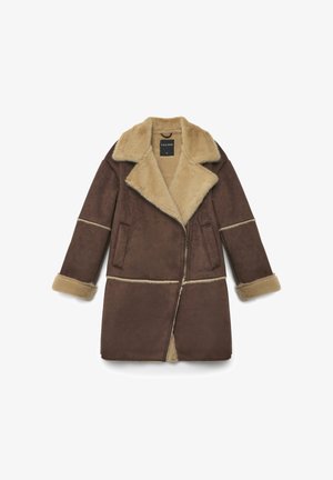 Manteau en fausse peau de mouton marron avec un large col, deux poches avant, et une doublure beige contrastante sur les poignets et les coutures. Fermeture éclair à l'avant.
