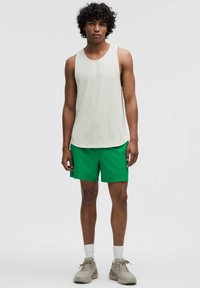 Hellgrau geschnittenes Tanktop mit vertikalen Streifen, kombiniert mit leuchtend grünen Shorts. Das Outfit zeichnet sich durch eine lässige Passform und gestapelte Stofftexturen aus.