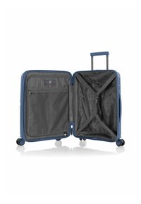 Valigia rigida blu con un interno organizzato, dotata di tasca in rete, cinghie e ruote scorrevoli. Design con zip chiusa.