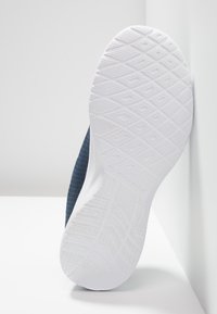 Scarpa con parte superiore in tessuto navy testurizzato e suola in gomma bianca con motivo a rombi per la trazione. Nome del marchio visibile sulla suola.
