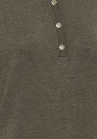 Chemise henley vert foncé en tissu textur�é, dotée d'une patte de boutonnage à trois boutons avec des boutons en métal argenté. Design simple et matériau doux.