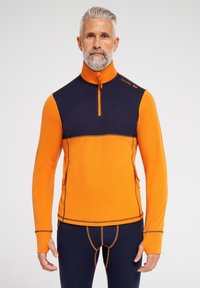 Orange og marineblå pullover med lynlås i halsen, lavet af et glat materiale. Har kontrastsyninger og sidelommer for funktionalitet.
