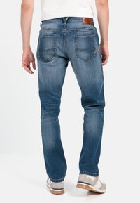 Dunkelblaue Denim-Jeans mit geradem Schnitt, zwei Gesäßtaschen und einem braunen Lederpatch am Bund. Glatte Textur.