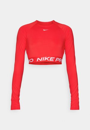 Rode lange mouwen crop top gemaakt van rekbaar materiaal, met een ronde hals en een witte "NIKE PRO" band aan de zoom. Gladde textuur, strakke pasvorm.