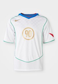 Camiseta de fútbol blanca con ribete verde, logo dorado circular con el '90', cuello azul y acento rojo en la manga izquierda. Textura de patrón a cuadros.