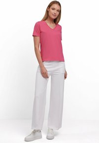 Roze V-hals t-shirt van zachte stof, gecombineerd met witte wijde broek en witte sneakers. Eenvoudig ontwerp met korte mouwen en geen patronen.