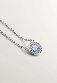Collar de cadena de plata que presenta una gema redonda de color azul claro rodeada de pequeños cristales transparentes en un engaste circular.