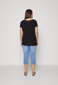 Crni kratki rukavić s izrezom u obliku valova, u kombinaciji s svijetloplavim uskim kapri trapericama. Osnovna, lagana tkanina s glatkom teksturom.